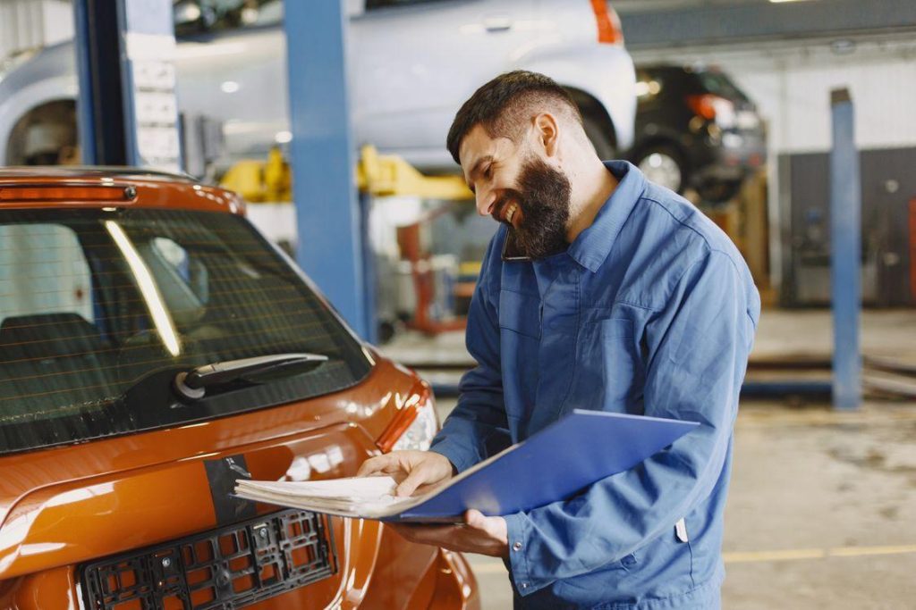 Technician inspecting vehicle damage and documenting collision impact for insurance claim processing