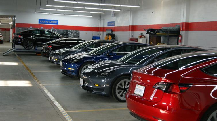 Row of Tesla vehicles inside E3 Collision's repair bay beneath Car-O-Liner equipment signage