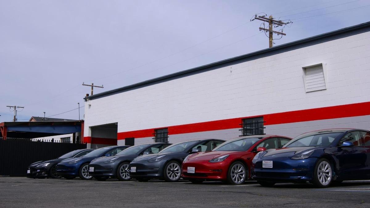 Tesla vehicles parked in a row outside the E3 Collision shop building